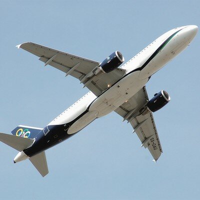 A commercial airplane soaring through a clear blue sky, captured from below as it ascends with its landing gear still visible.