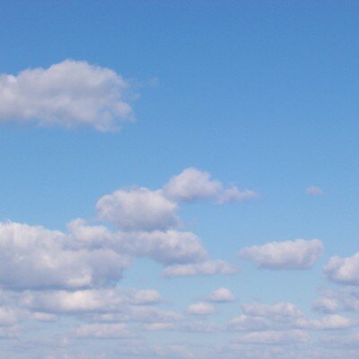 A clear blue sky dotted with fluffy white clouds, capturing the bright and pleasant weather typical of Crete.