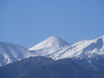 Snow-capped peaks of the White Mountains of Crete against a clear blue sky.